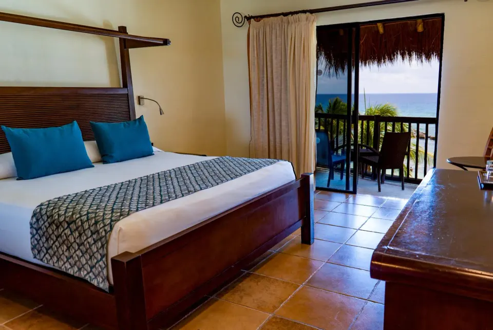 King bed guest room with balcony overlooking ocean at Catalonia Yucatan Beach.