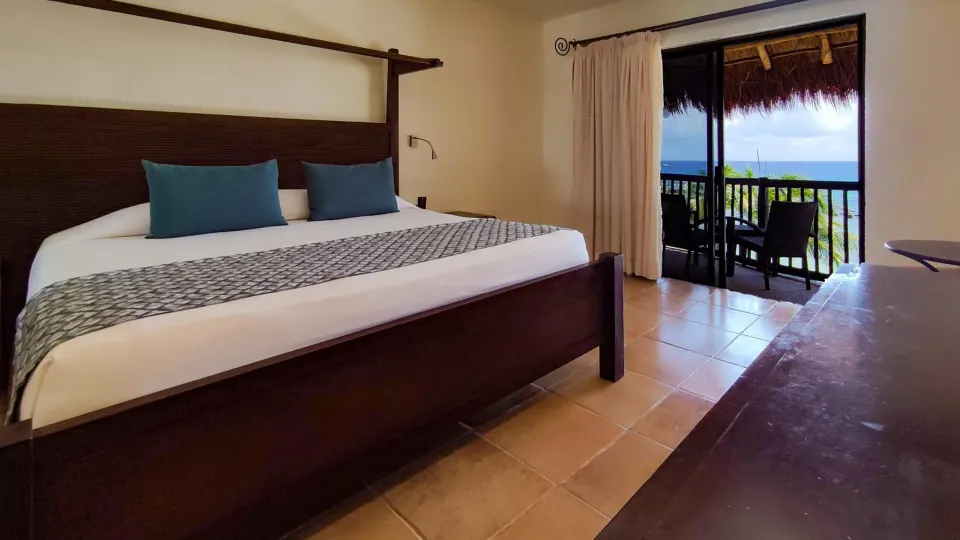King bed and seating area with TV in room at Catalonia Yucatan Beach.