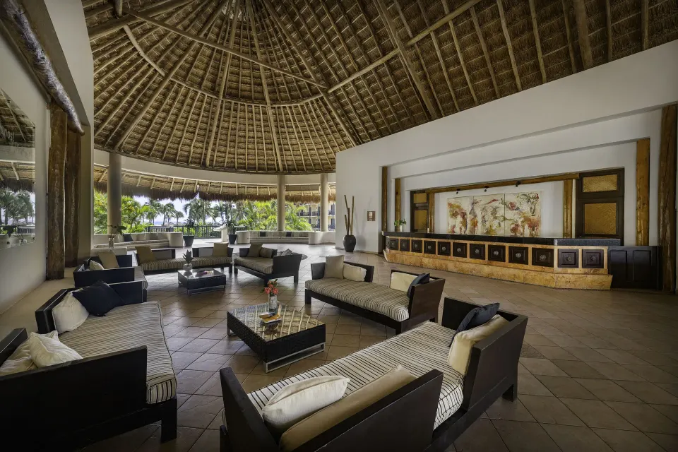 Open-air resort lobby seating area with palapa roof at Catalonia Yucatan Beach