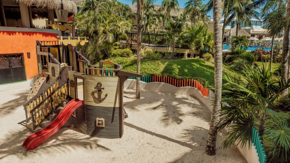 Ship-themed sandy playground with slide among palm trees at Catalonia Yucatan Beach