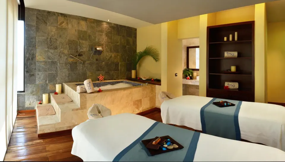 Couples spa treatment room with twin massage tables and jetted tub at Catalonia Yucatan Beach