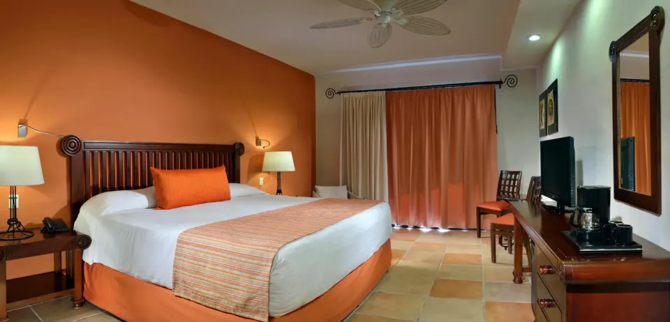 Warm-toned guest room with king bed and orange accents at Catalonia Yucatan Beach