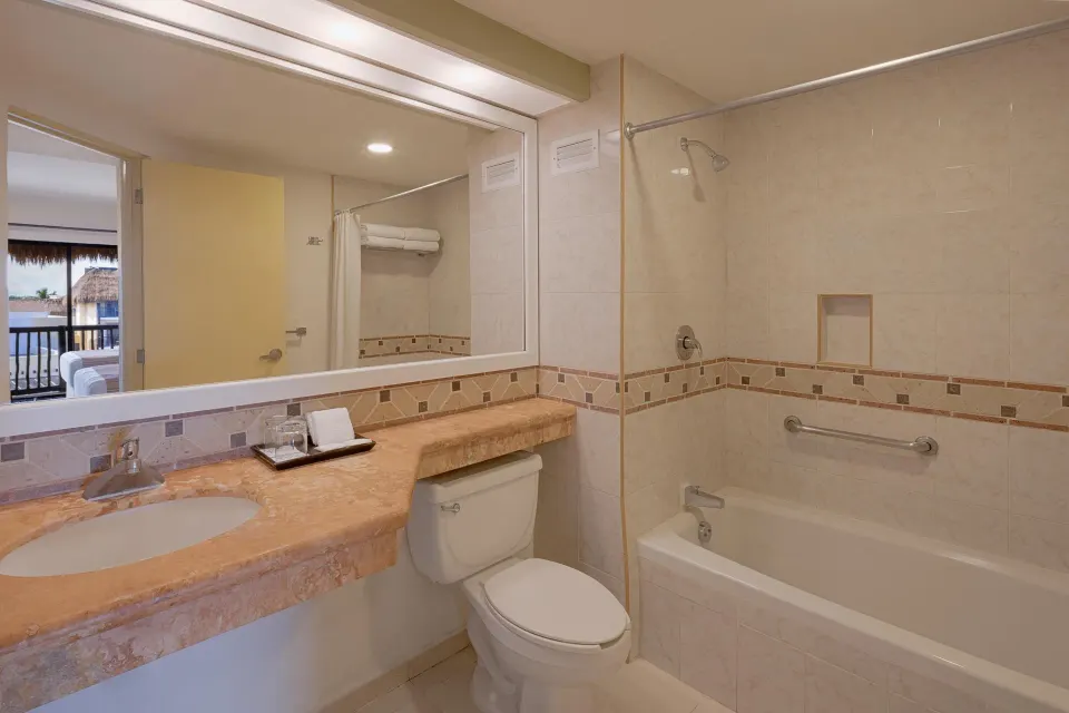 Guest room bathroom with tub-shower combination at Catalonia Yucatan Beach.