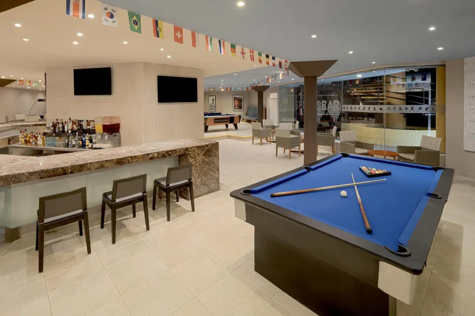 Open bar lounge with pool table and flags overhead at Catalonia Yucatan Beach