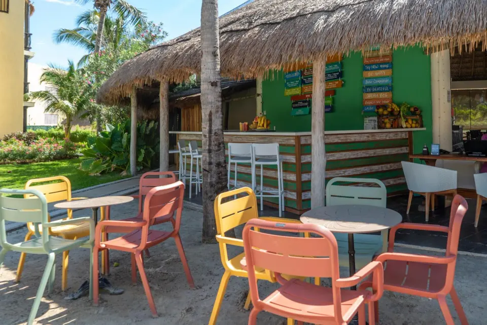 Outdoor palapa bar seating with colorful chairs at Catalonia Yucatan Beach