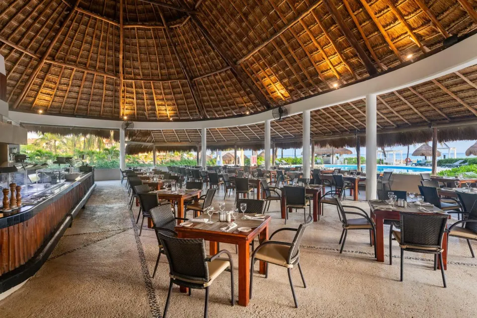 Open-air palapa dining area at Catalonia Yucatan Beach with tables and ocean views.