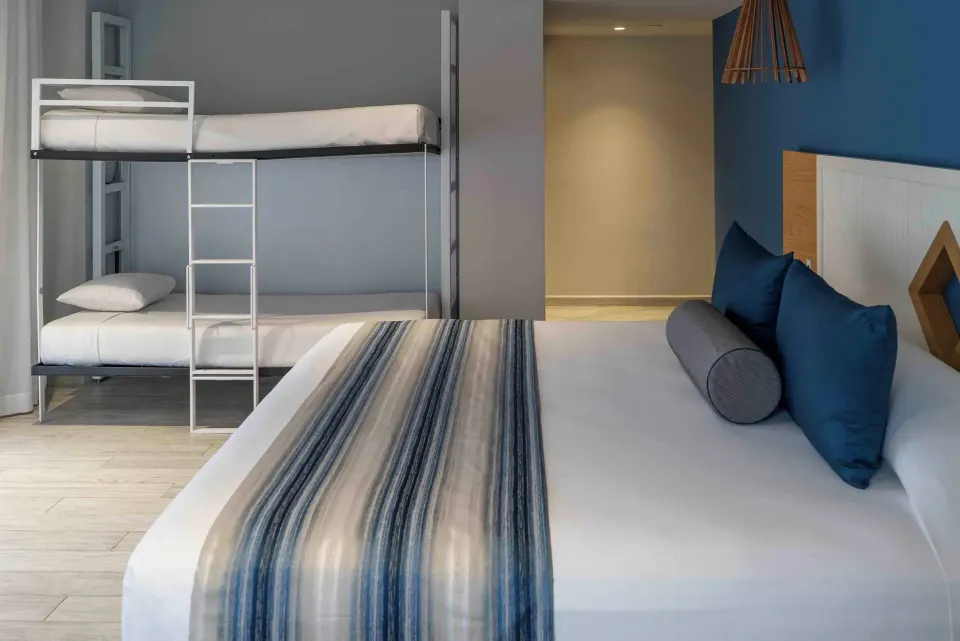 Premium Deluxe Room at Catalonia Yucatan Beach with king bed and bunk beds in the corner.