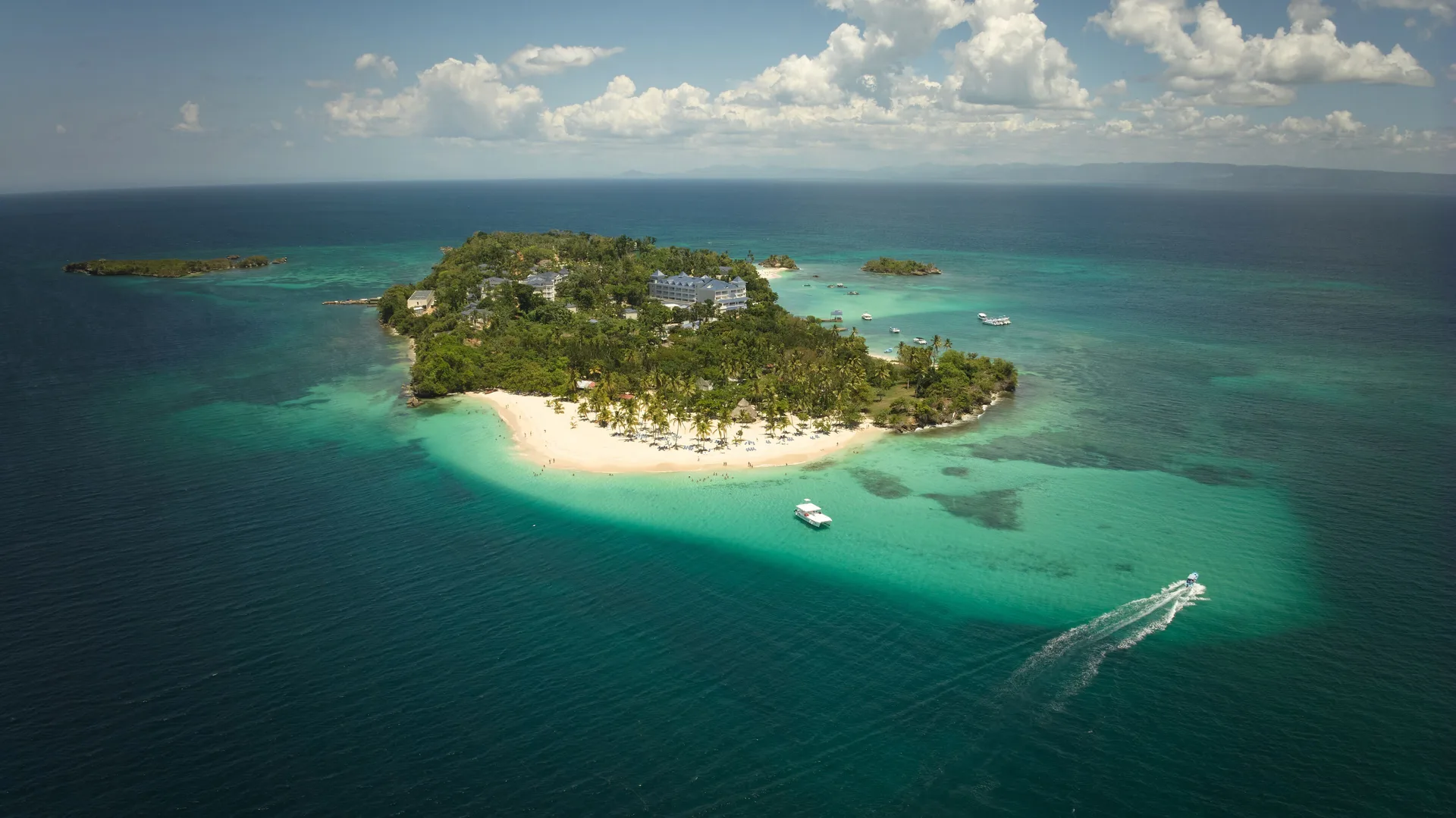 Aerial view of Cayo Levantado Resort with beaches, boats, and turquoise shallows.