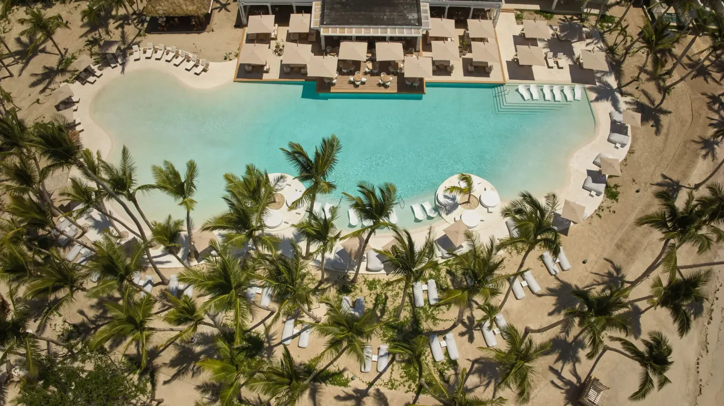 Aerial view of a beachside pool with palms and loungers at Cayo Levantado Resort.