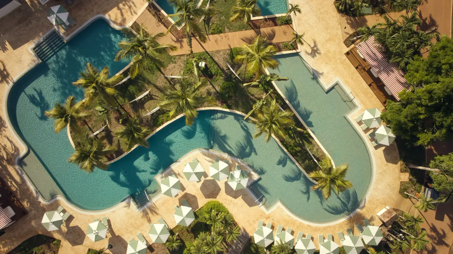Aerial view of winding pools and palm landscaping at Cayo Levantado Resort.