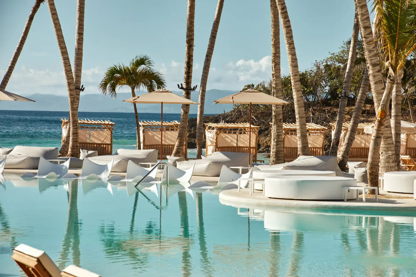 Beachfront pool with palms and ocean beyond at Cayo Levantado Resort.