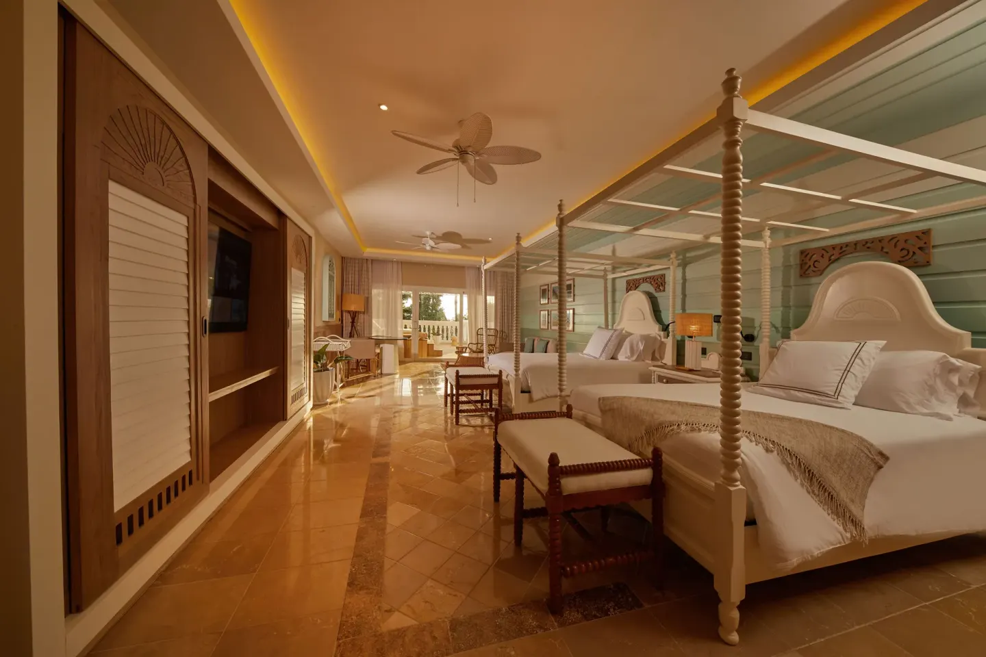 Wide guest room with two canopy beds and balcony doors at Cayo Levantado Resort.