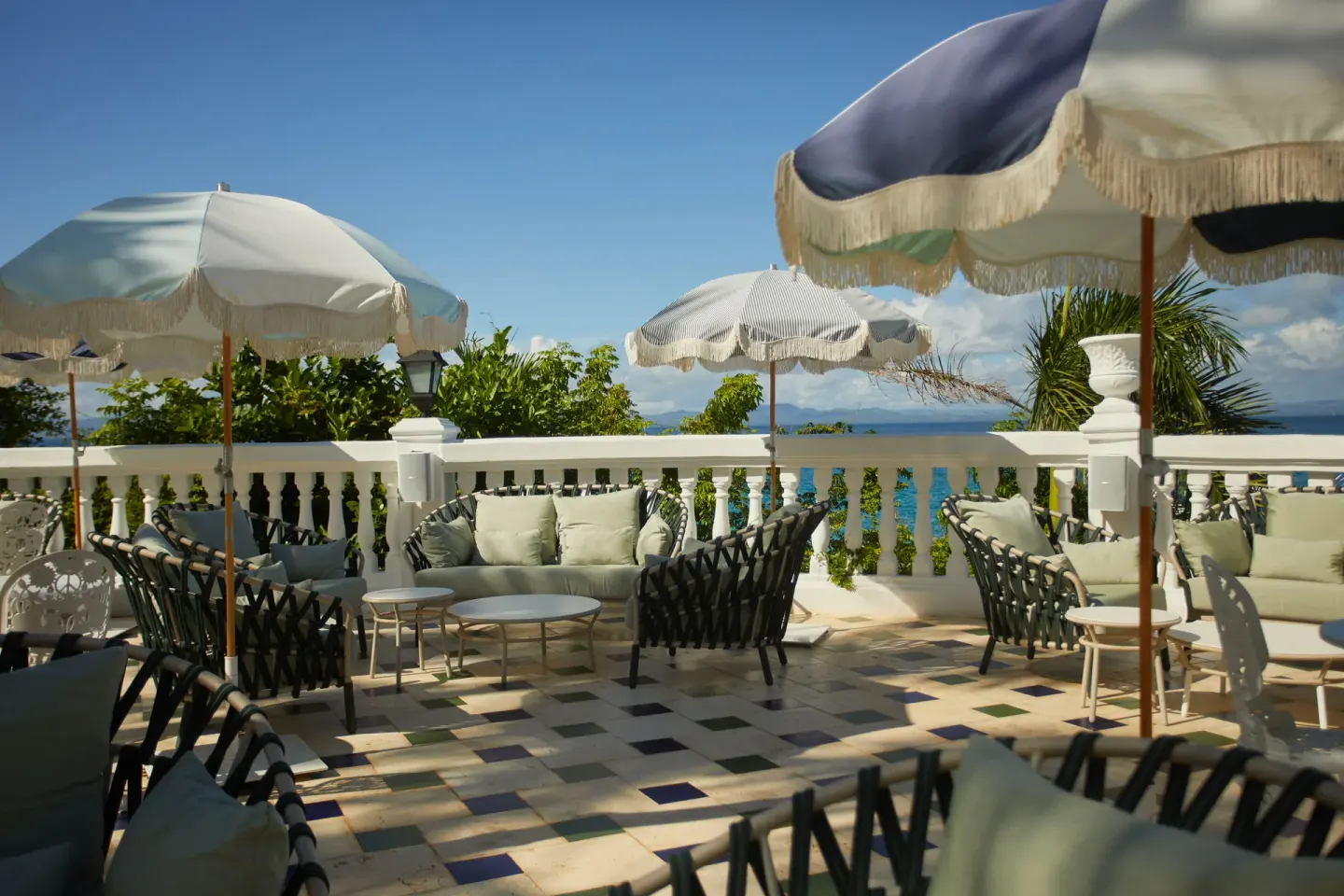 Ocean-facing terrace seating with fringed umbrellas at Cayo Levantado Resort.