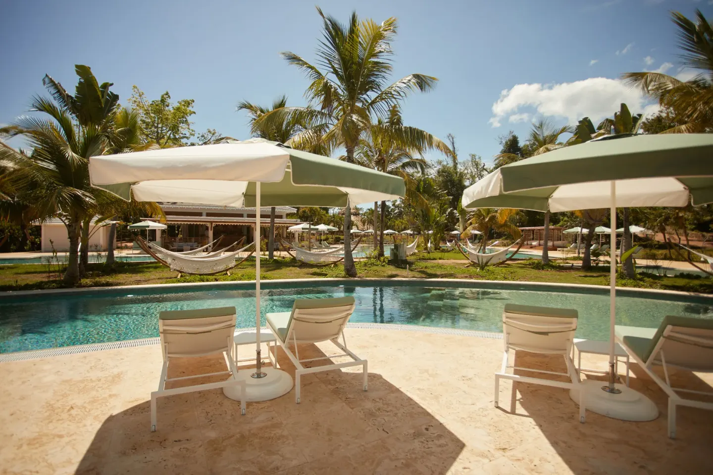 Poolside loungers with umbrellas and palms at Cayo Levantado Resort.