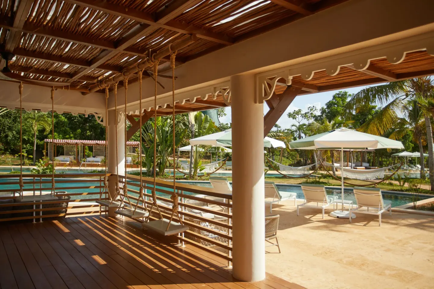 Shaded porch swings overlook the pool and hammocks at Cayo Levantado Resort.