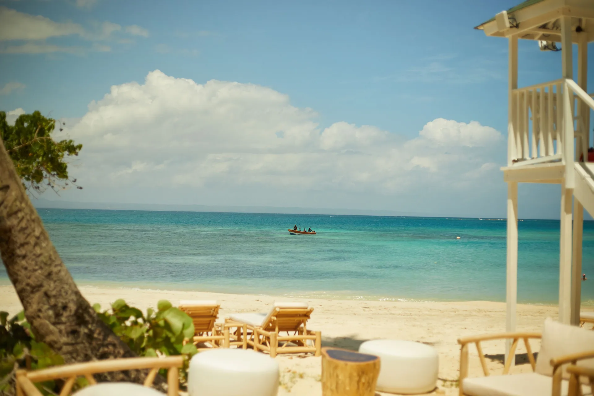 Beach seating overlooks turquoise water and a small boat at Cayo Levantado Resort.