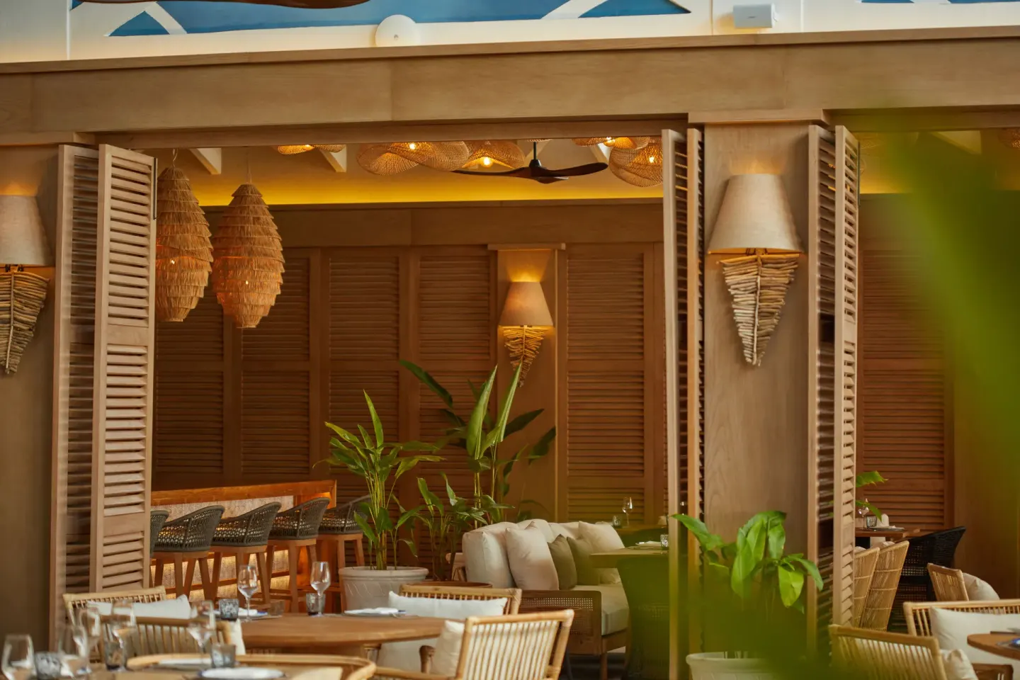 Open-air dining room with louvered shutters and woven lighting at Cayo Levantado Resort.
