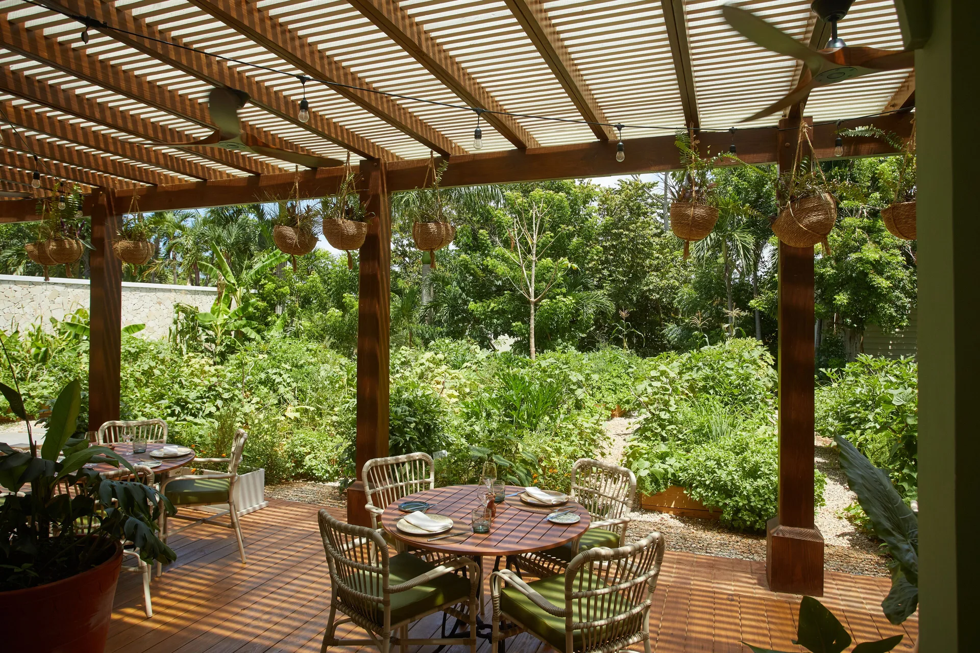 Garden terrace dining area with round tables and hanging planters at Cayo Levantado Resort.