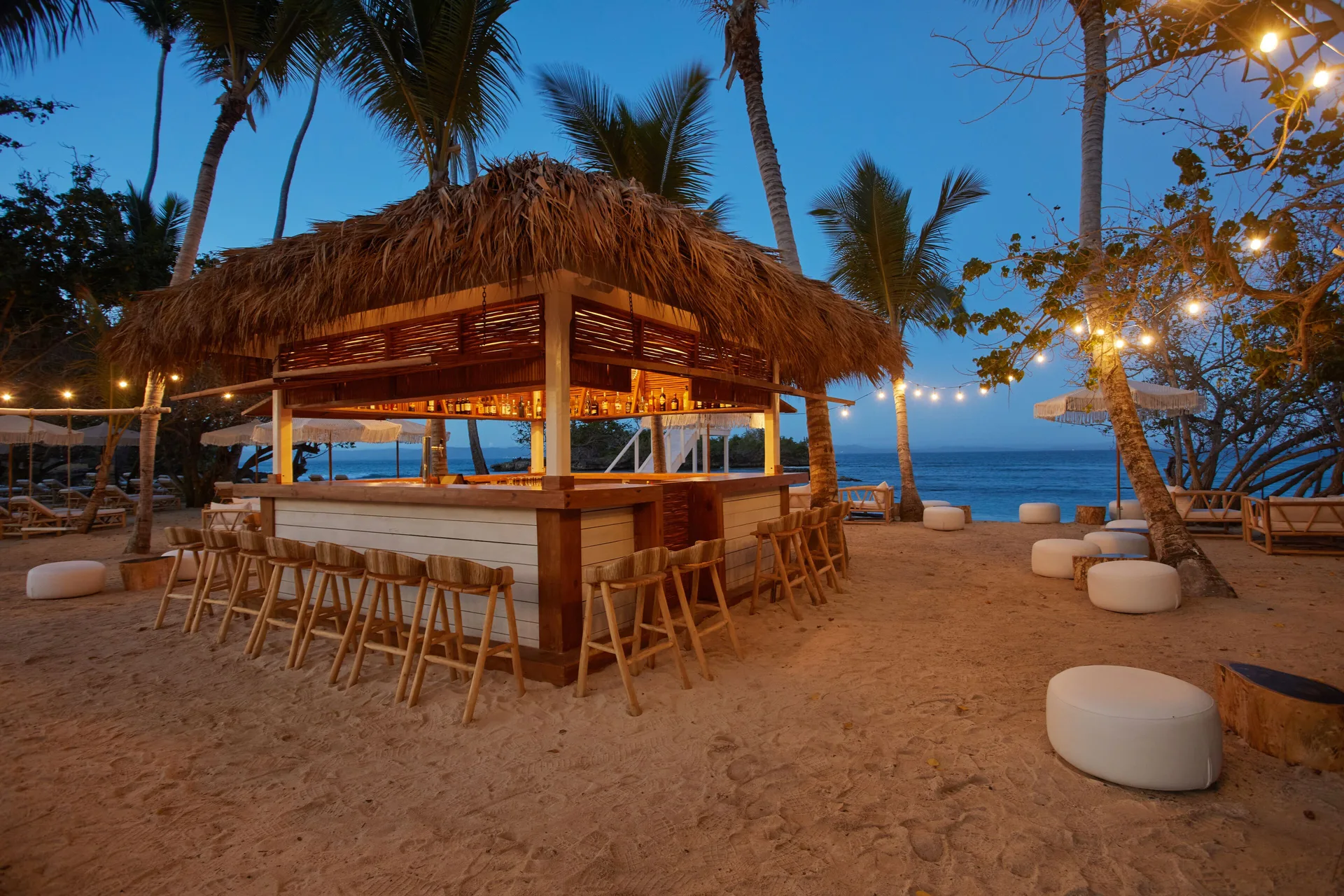 Thatched beach bar with stools and string lights at Cayo Levantado Resort.