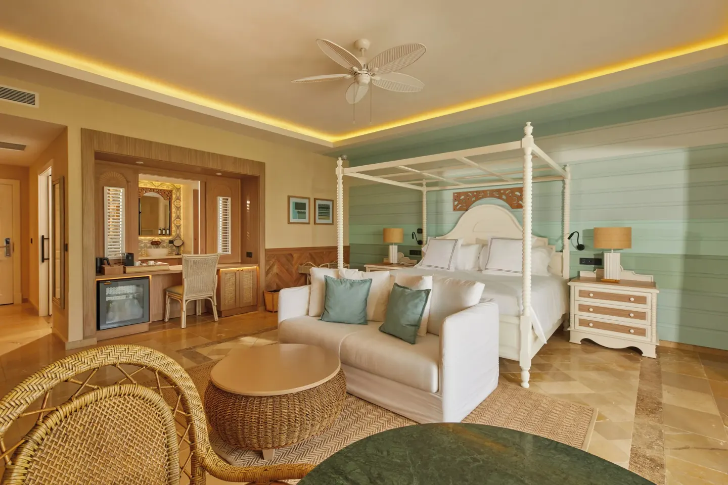 Junior Suite king canopy bed, sofa, vanity, and minibar at Cayo Levantado Resort.