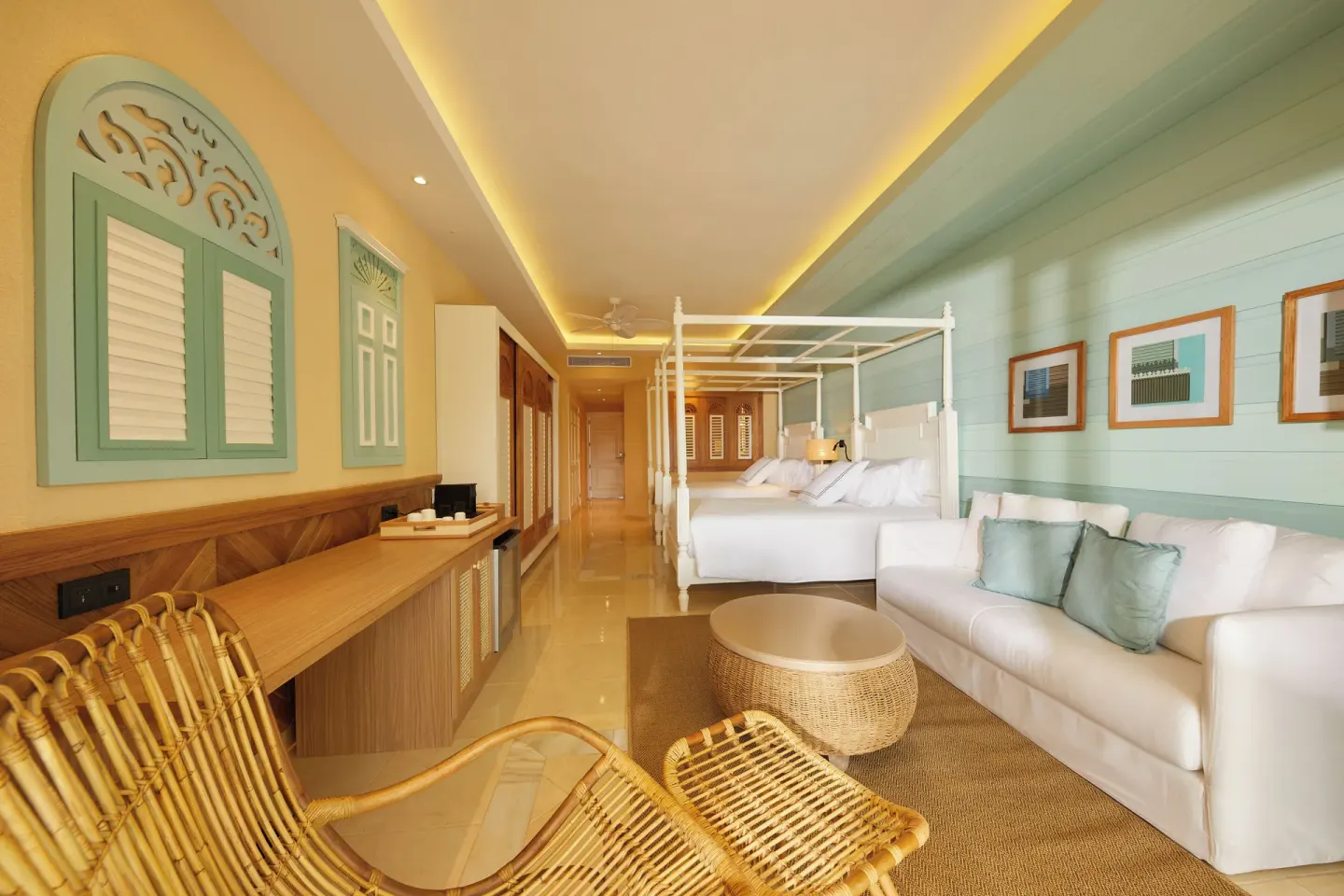 Junior Suite seating area with sofa, rattan chair, and two beds at Cayo Levantado Resort.