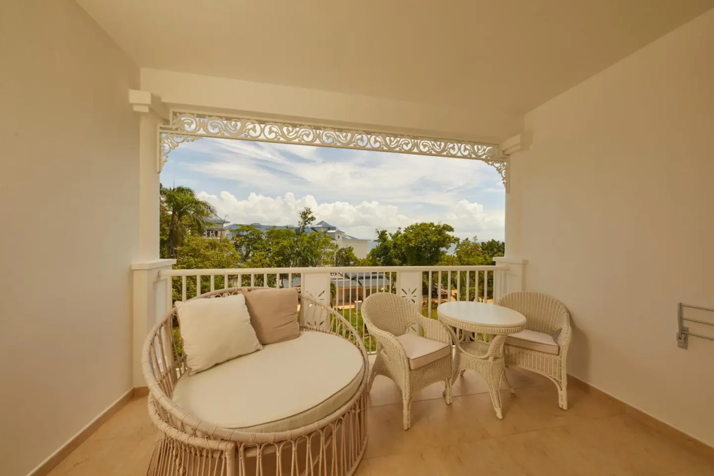 Junior Suite balcony with wicker seating and treetop view at Cayo Levantado Resort.