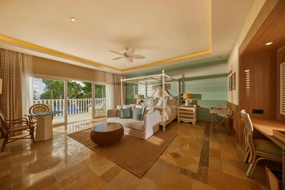 Junior Suite with four-poster bed, sitting area and balcony at Cayo Levantado Resort.