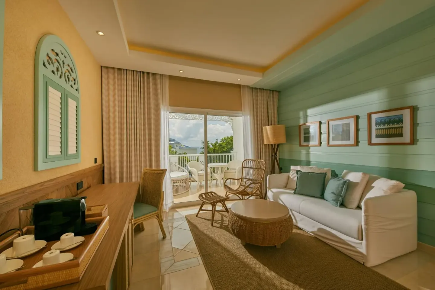 Junior Suite living area with sofa, desk and balcony at Cayo Levantado Resort.
