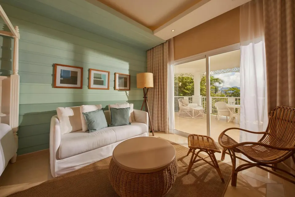 Junior Suite sitting area with sofa, wicker chair and balcony at Cayo Levantado Resort.