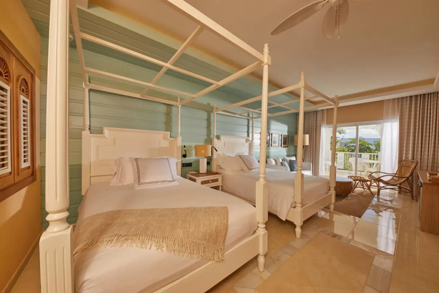 Junior Suite with two four-poster beds and balcony seating at Cayo Levantado Resort.