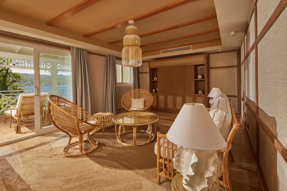 Bay view villa living room with rattan seating and balcony at Cayo Levantado Resort.