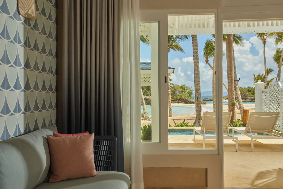 Villa sitting area with sliding doors to beach and palms at Cayo Levantado Resort.