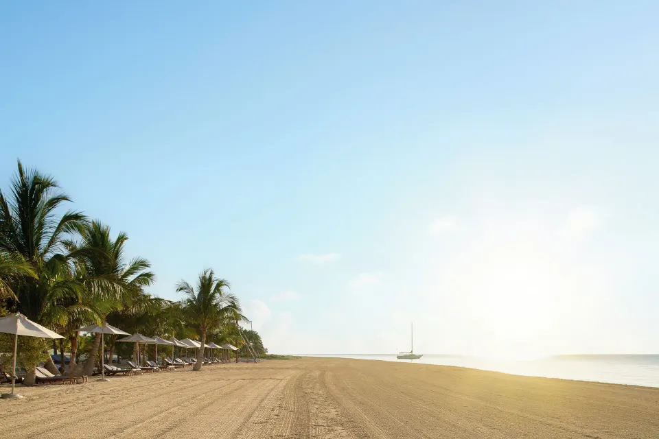 Wide sandy beach with lounge chairs and palms at Chablé Maroma