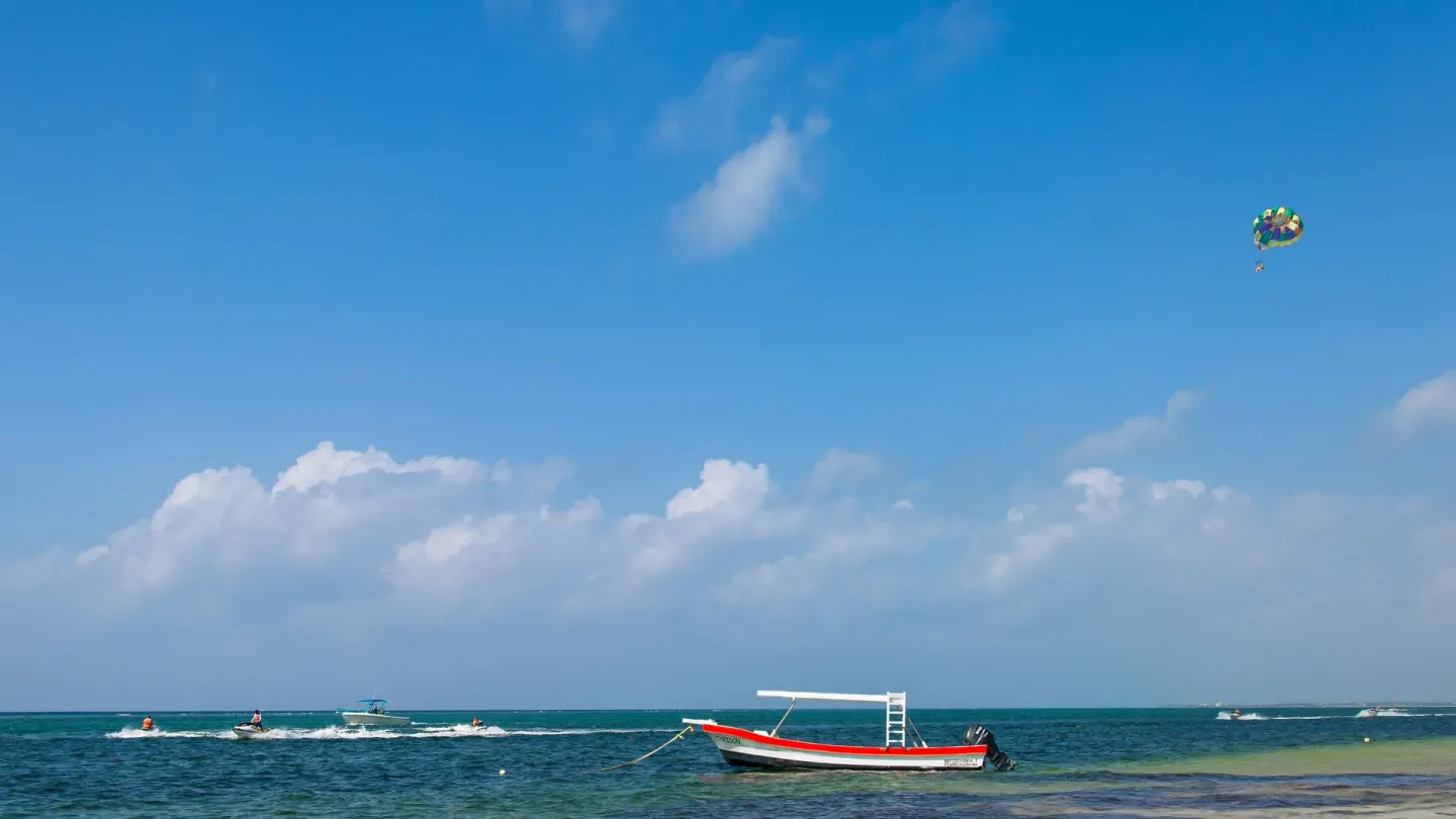 Caribbean sea with boats, parasailing, and blue sky near Chablé Maroma.