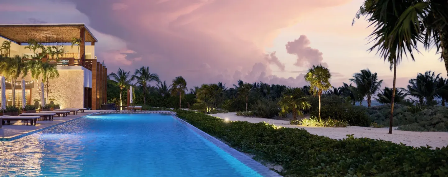 Evening pool scene with lit pathways and a dramatic sky at Chablé Maroma.