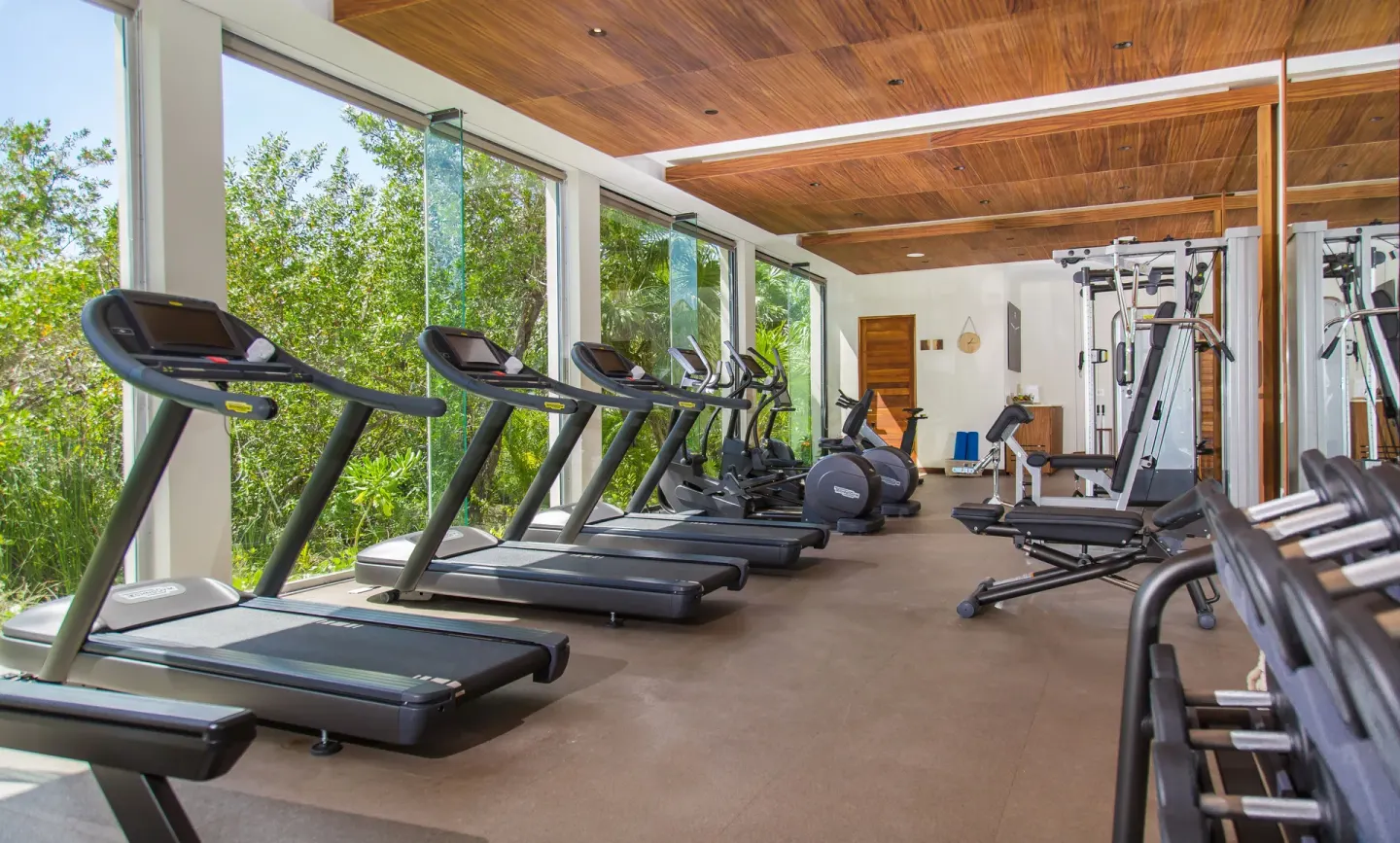 Fitness room with treadmills, weights, and garden-facing windows at Chablé Maroma.