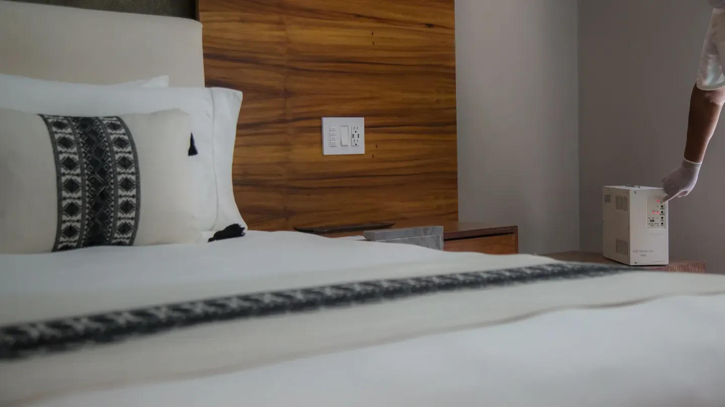A staff member places a device beside a made bed in a guest room at Chablé Maroma.