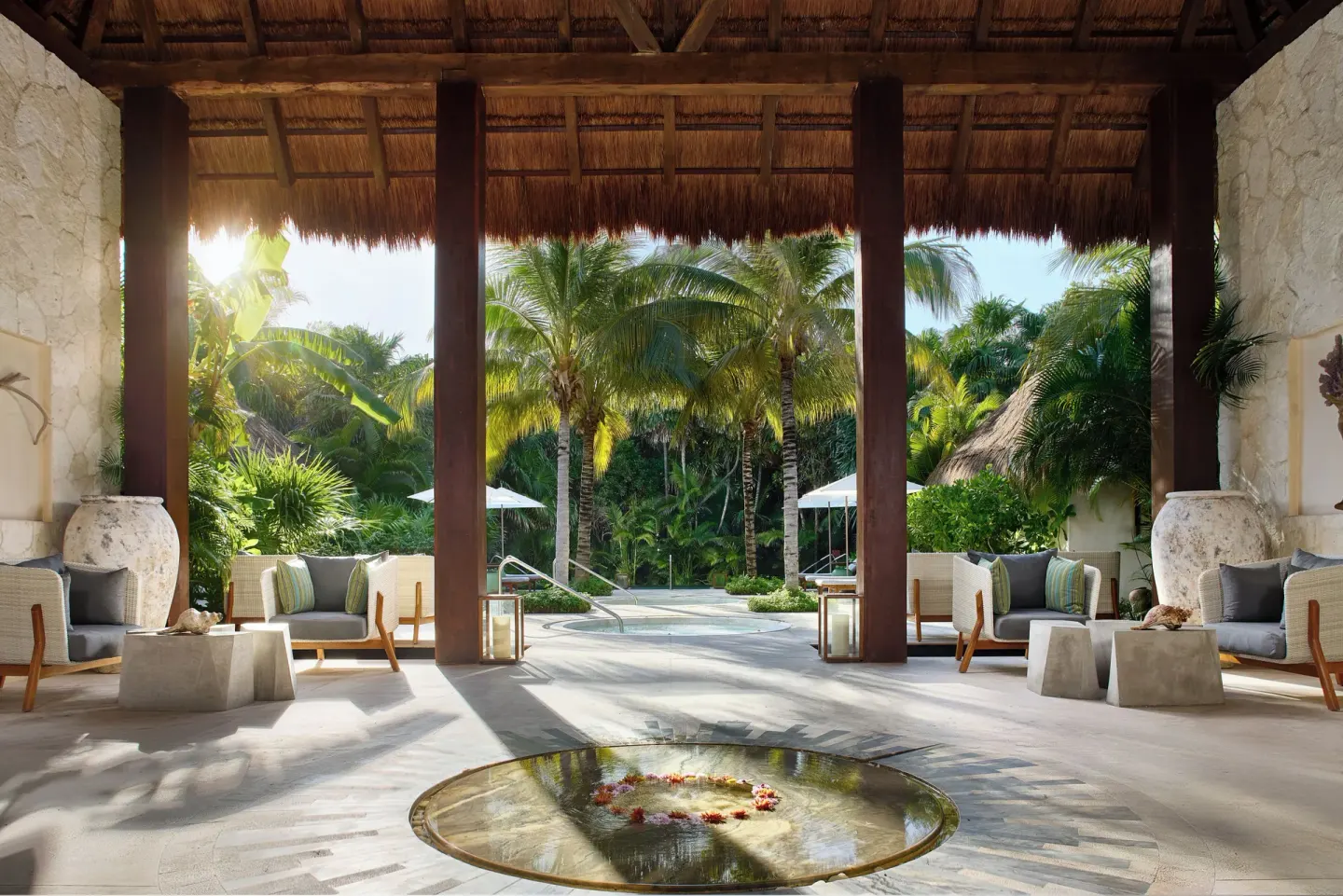 Open-air lobby with thatched roof, lounge seating, and tropical garden at Chablé Maroma.