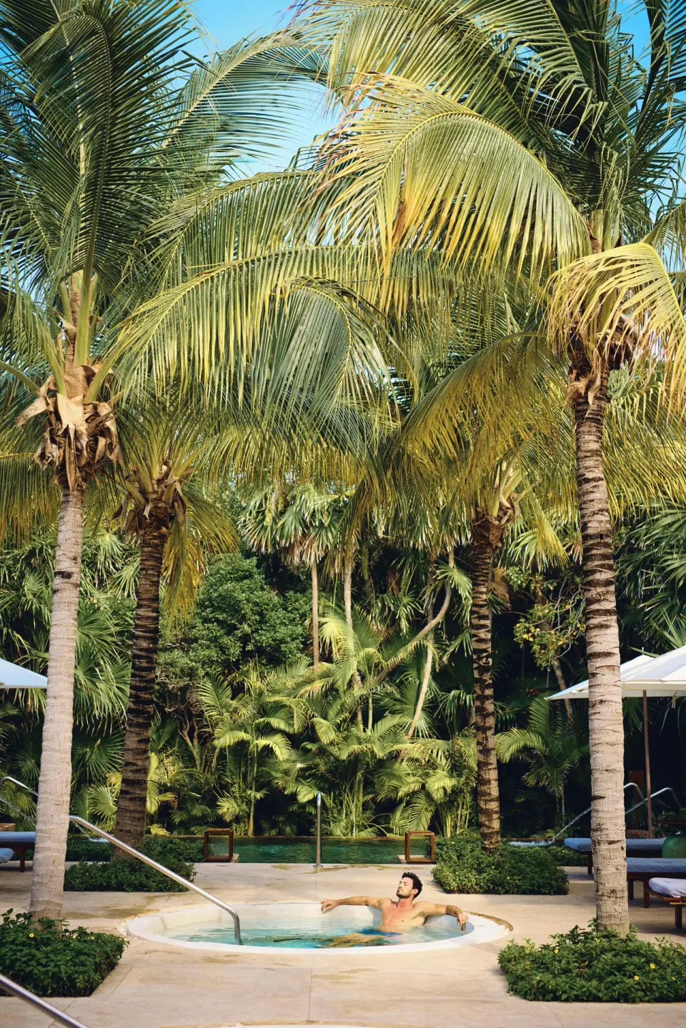 Guest relaxing in a small pool surrounded by tall palms at Chablé Maroma.