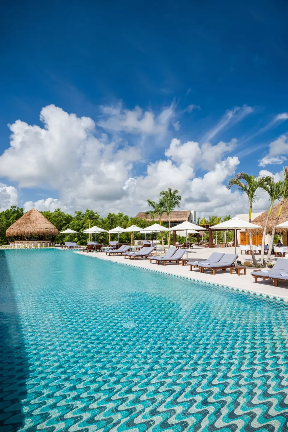 Wide view of the resort's patterned-tile pool and lounge chairs at Chablé Maroma