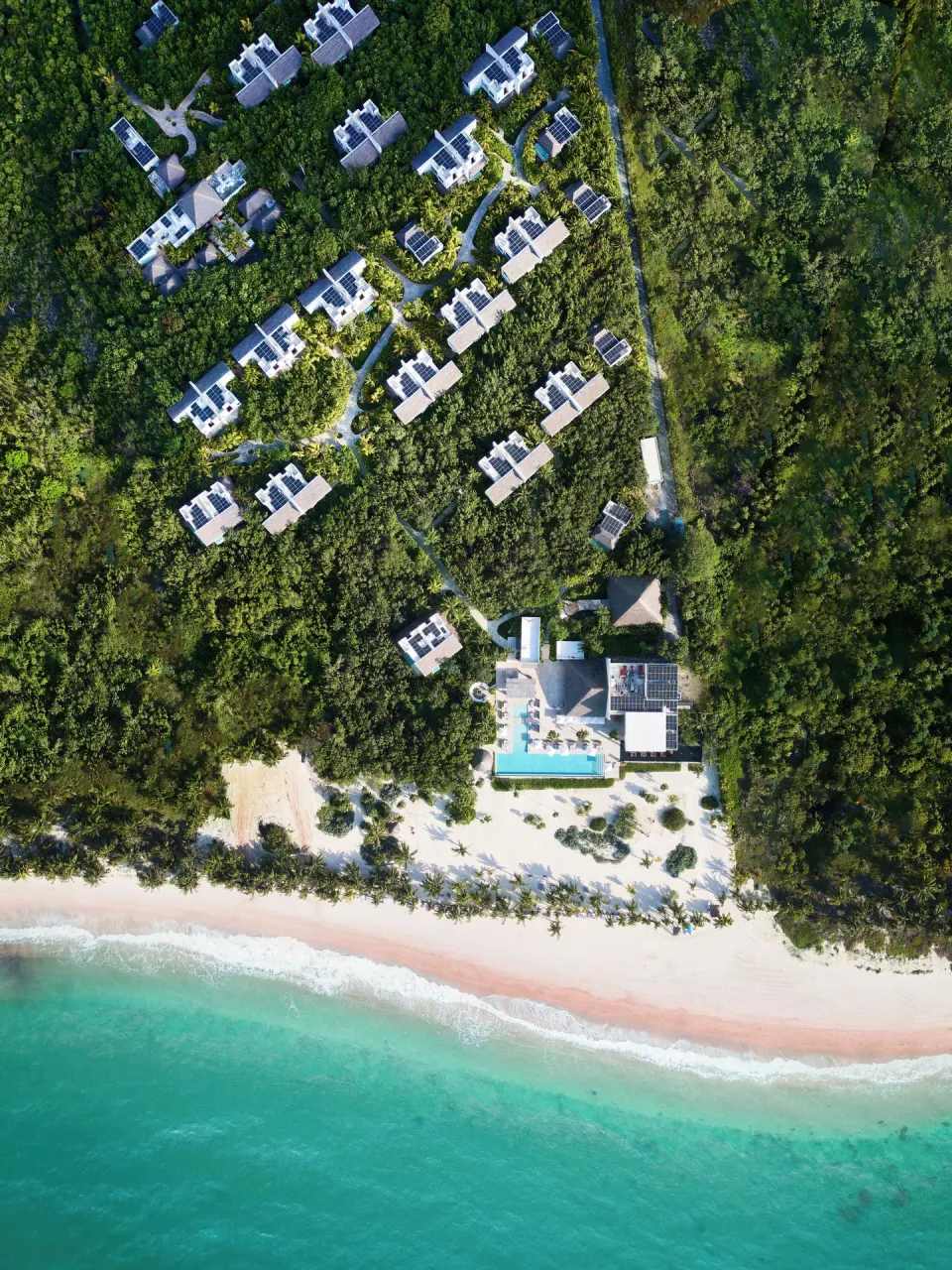 Aerial view of Chablé Maroma villas set in jungle beside the beach and turquoise sea.