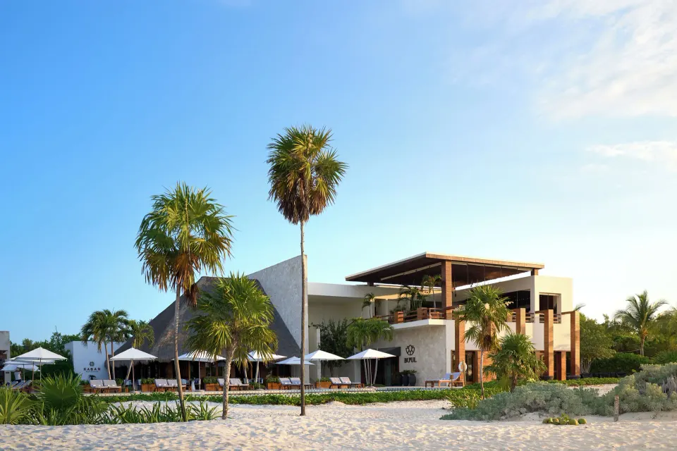Beachfront resort buildings and palm trees at Chablé Maroma on a sunny day