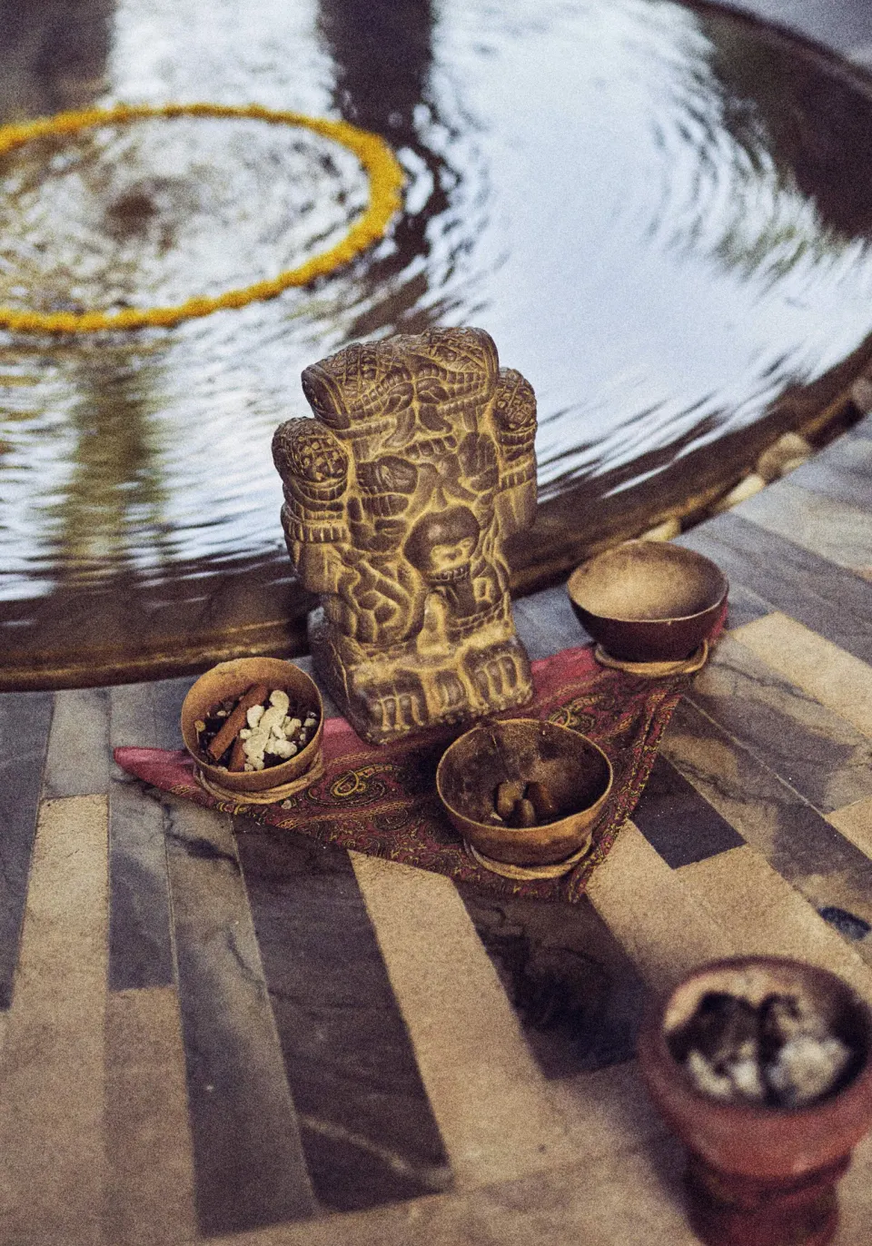 Carved ritual figure and bowls beside a reflecting pool at Chablé Maroma.