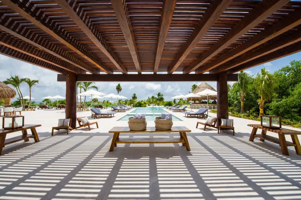 Shaded pergola framing the pool deck and loungers at Chablé Maroma