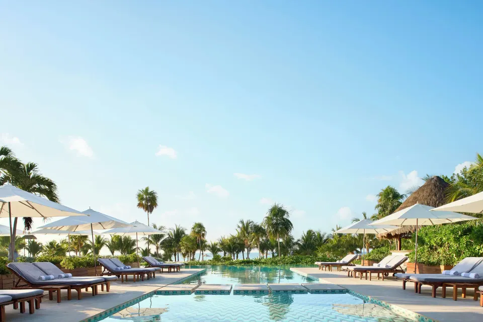 Twin rows of sunbeds flanking the resort pool at Chablé Maroma
