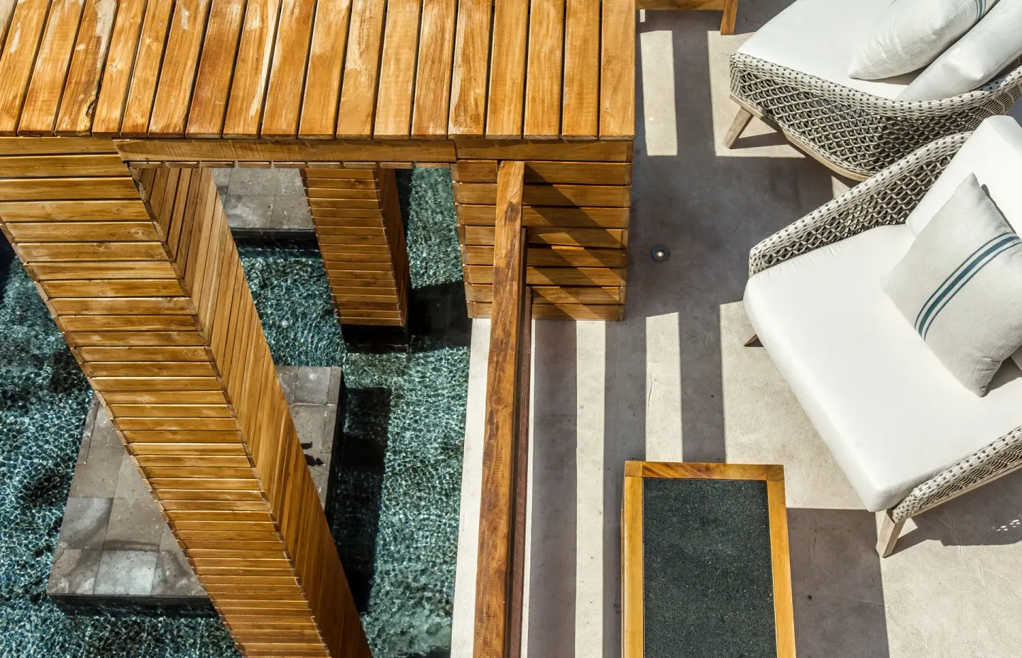 Overhead view of a wooden bridge, water feature and cushioned terrace seating at Chablé Maroma.