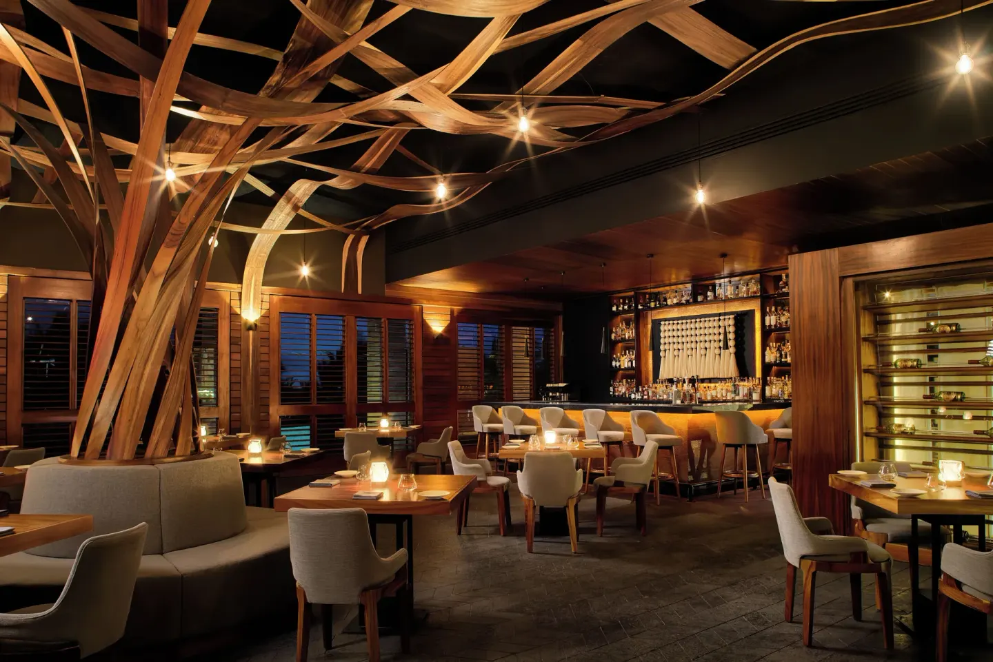 Warmly lit bar and dining room with sculptural wood ceiling at Chablé Maroma.