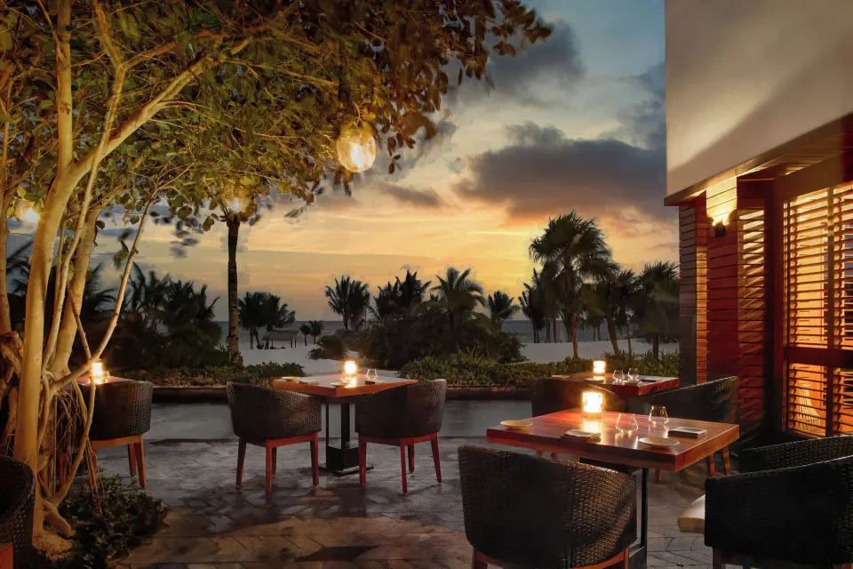 Outdoor terrace dining at dusk with candlelit tables and ocean view at Chablé Maroma