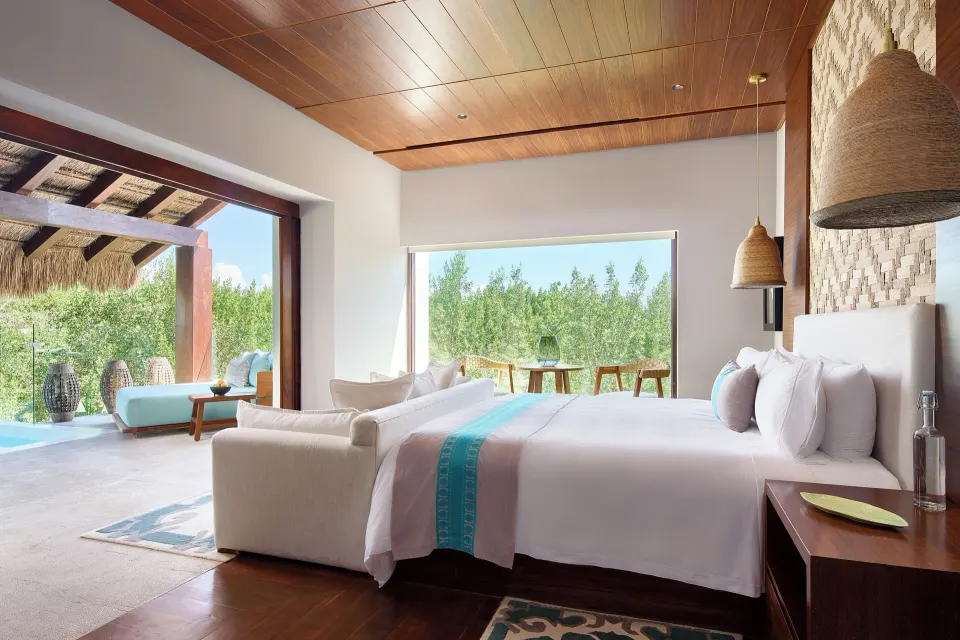 Treetop Pool Villa king bed beside large windows and terrace at Chablé Maroma.