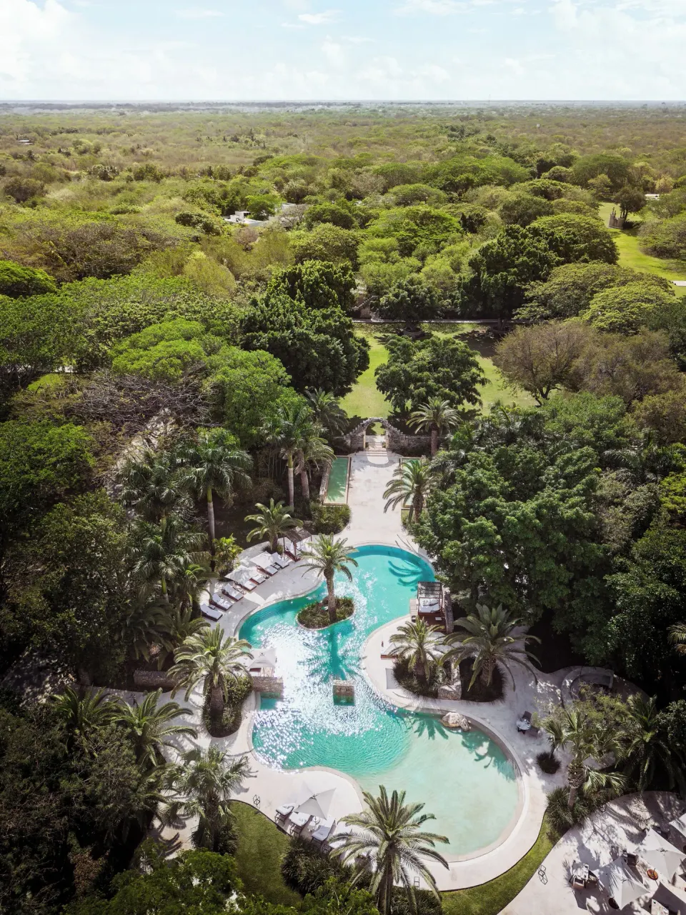 Aerial view of resort grounds and pool amid forest canopy at Chablé Yucatán